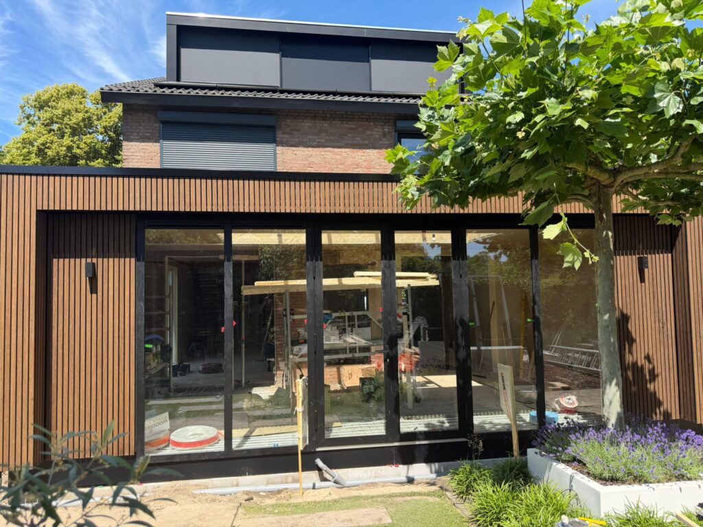 Moderne uitbouw in Amsterdam met verticale houten gevelbekleding en grote glazen pui